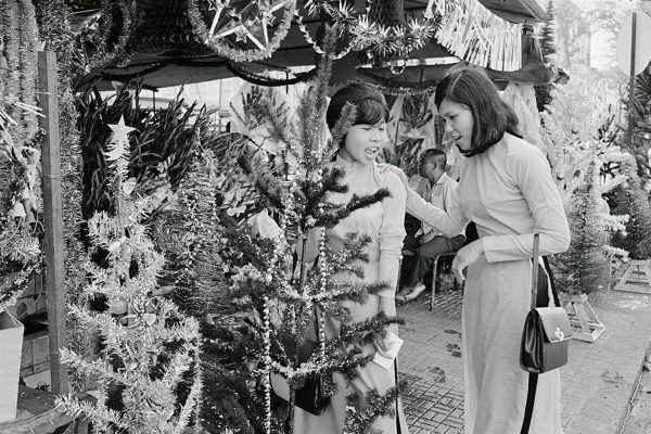 14 Dec 1967, Saigon, South Vietnam --- Saigon: Christmas Shopping. War worries seem forgotten as these two Vietnam girls shop for a Christmas tree in Saigon. Holiday is only ten days off. --- Image by © Bettmann/CORBIS
